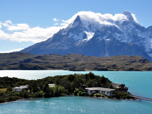 Ausblick auf den Lago Pehoé und die dahinter aufragenden Berge und das am See liegende Hotel.