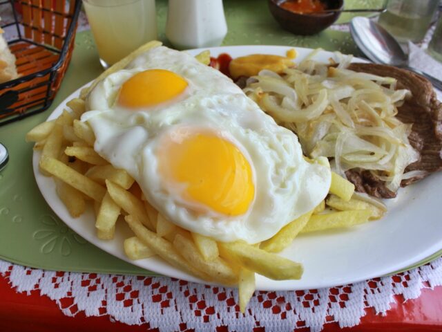 Bistec a lo pobre - Rindschnitzel mit gebratenem Zwiebel, Pommes und Spiegelei, ein sehr typisches Gericht der Einheimischen in Chile. Findet man auf beinahe jeder Speisekarte wieder.