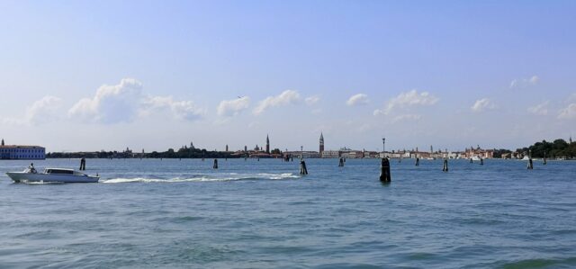 Schon die Anreise mit dem Linienschiff von Punta Sabbioni nach Venedig ist berauschend. Der warme Fahrtwind braust über das Deck, die salzige Meeresluft lässt erahnen, wie die Stadt errichtet wurde, nämlich auf Stelzen in der Lagune. Den Blick auf den Horizont gerichtet, nähert sich Venedig immer weiter bis man schon mit freiem Auge den beeindruckenden Dogenpalast erkennen kann.