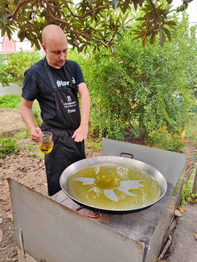 Chefkoch Miguel erklärt uns, wie wichtig es ist, dass die Pfanne gerade steht, damit die Paella später nicht anbrennt.